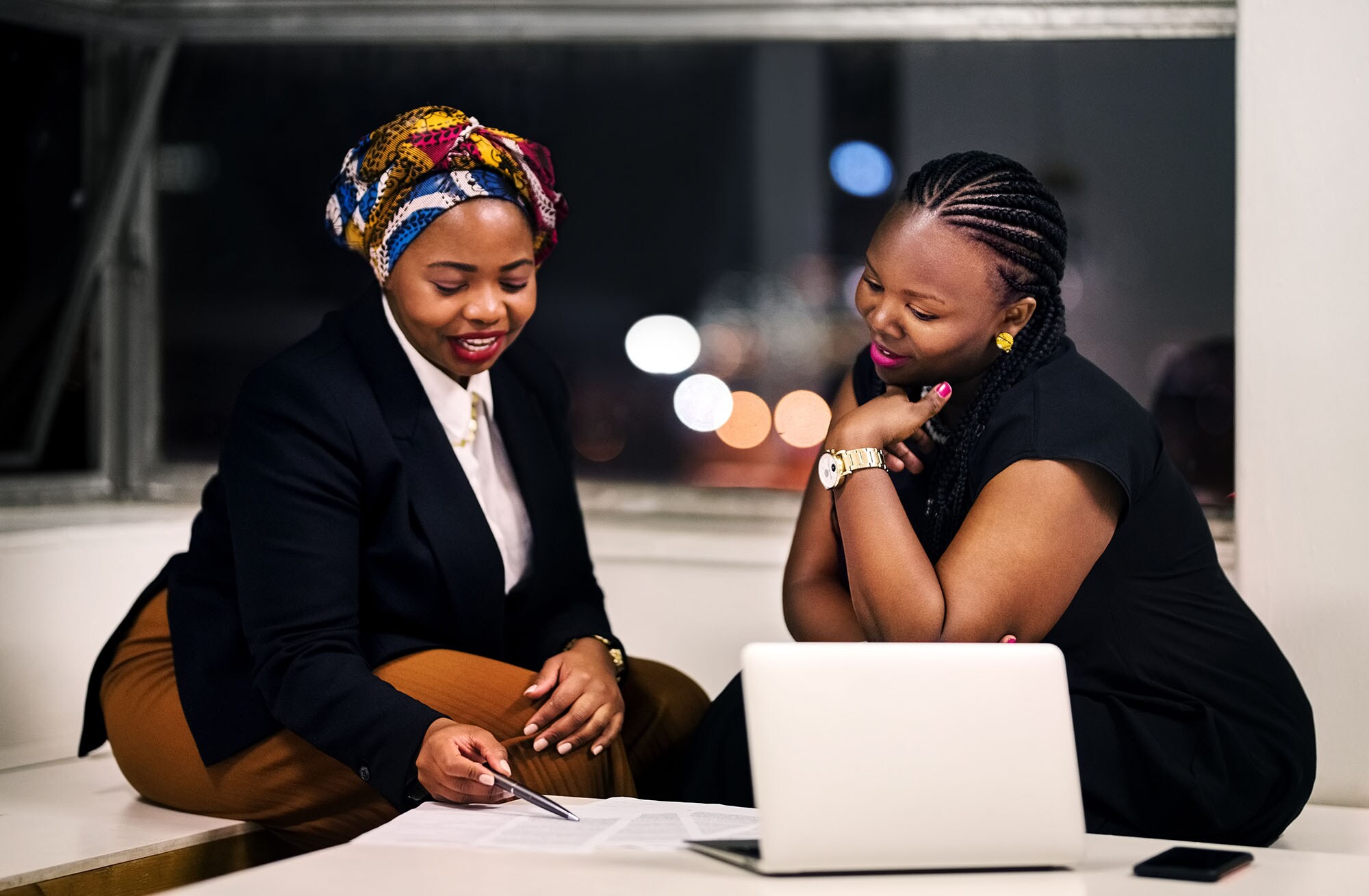 Two women listening to a podcast on their computer.