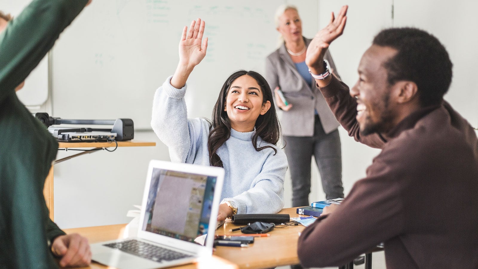 People with their hands up sitting in an office room.