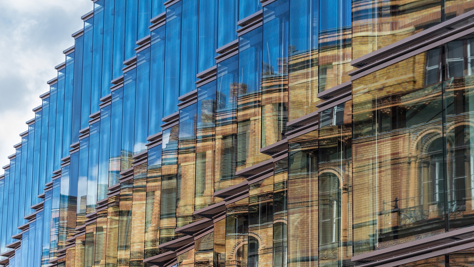 a glass city building eith a reflection of the opposite building