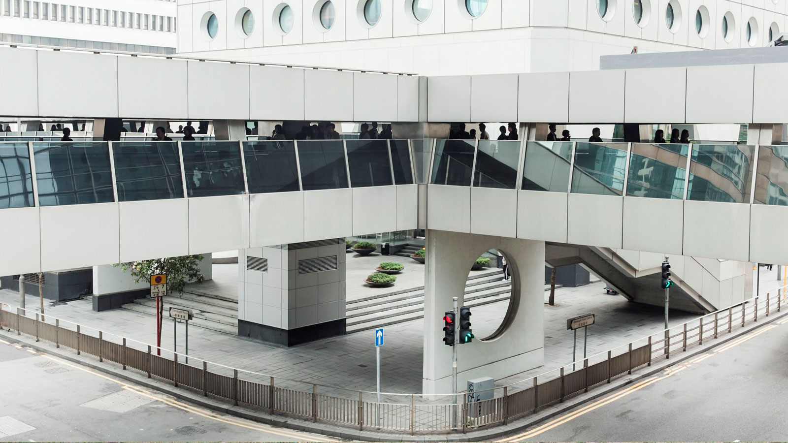 elevated walkway or bridge, designed with glass panels and supported by large white columns.